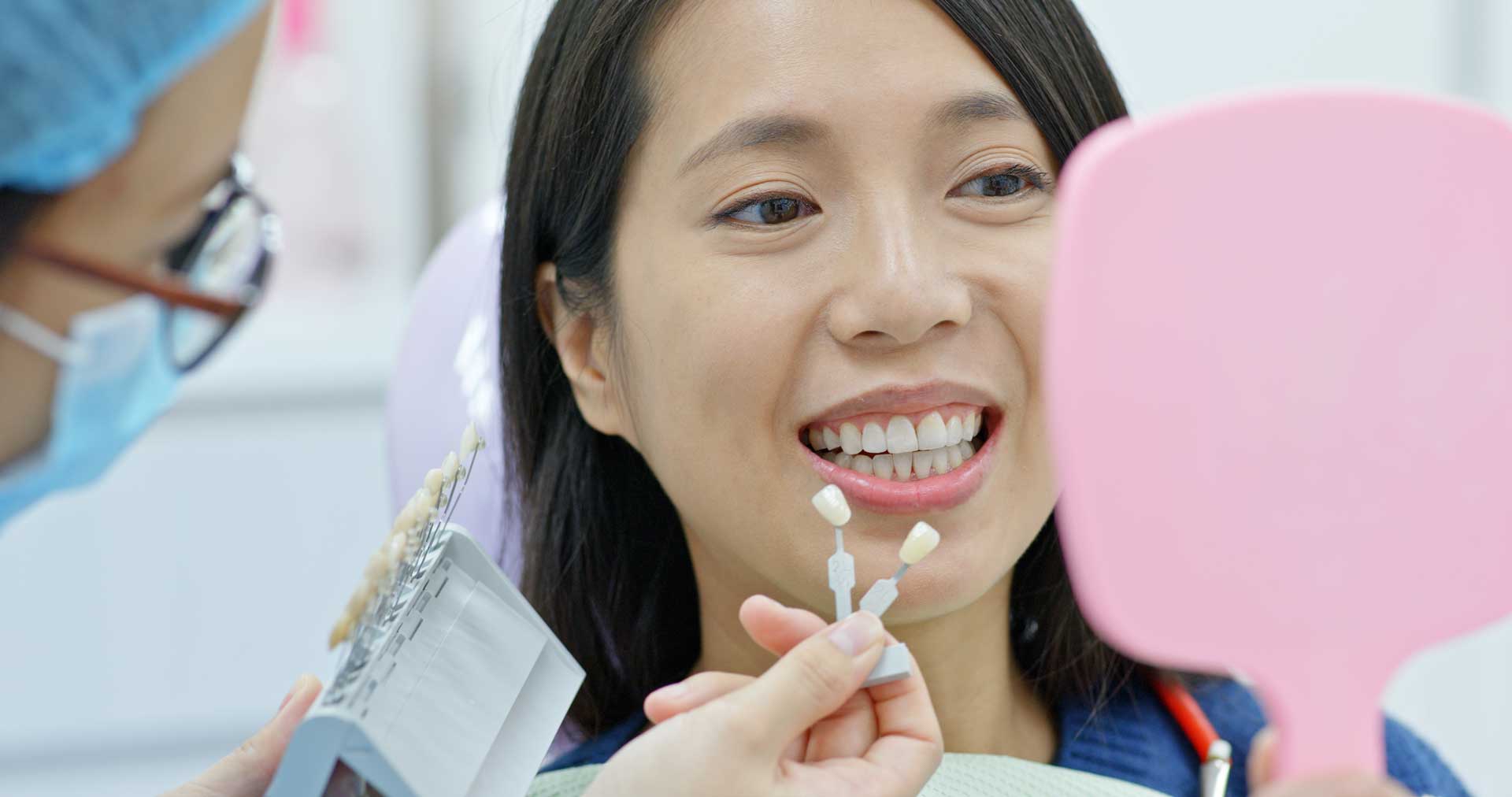 Asian female dentist checking out patient's teeth, and woman smiling